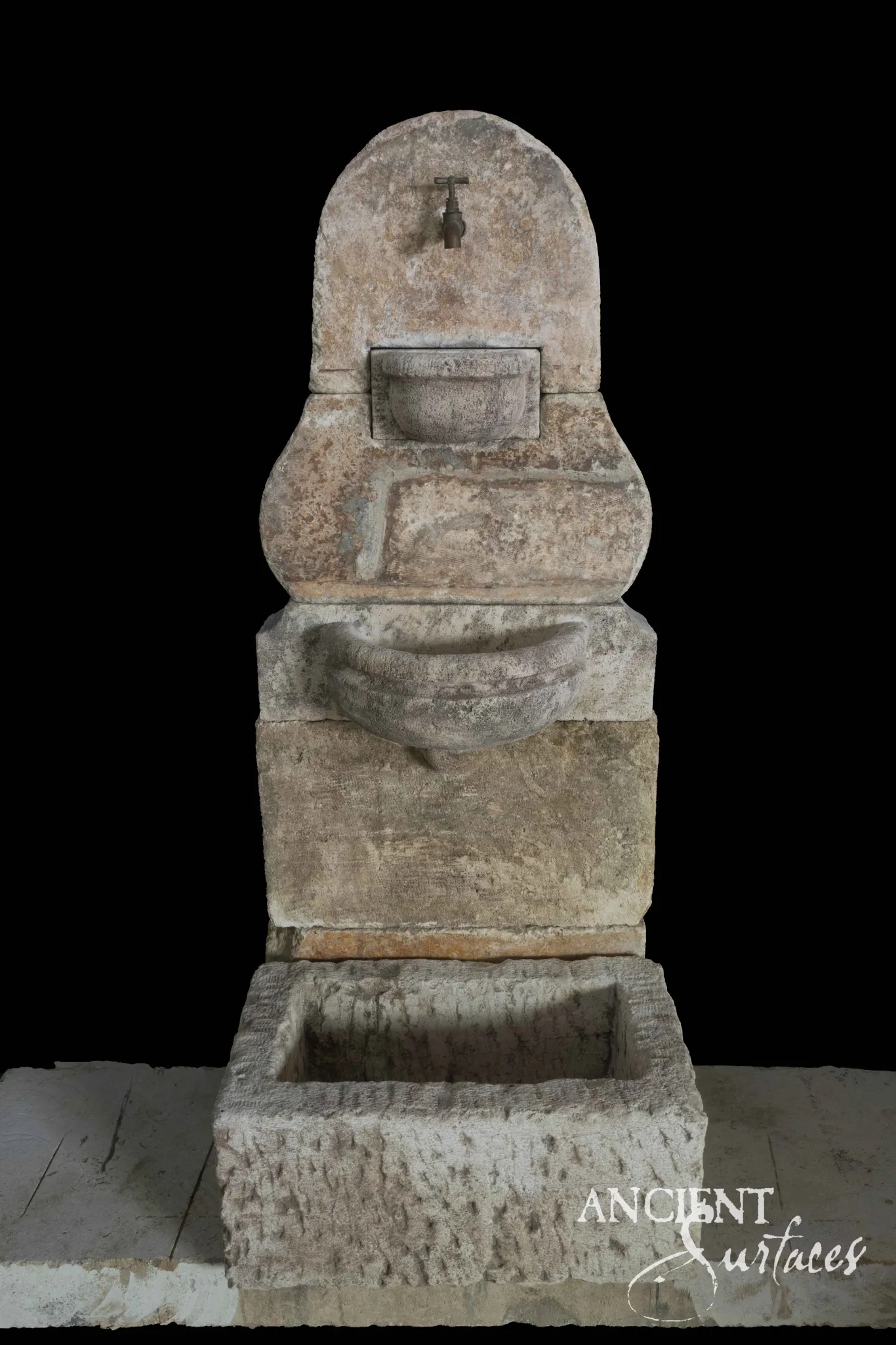 Reclaimed antique limestone wall fountain from Ancient Surfaces with a pear shaped backplate carved with a shell like panel over a rectangular basin