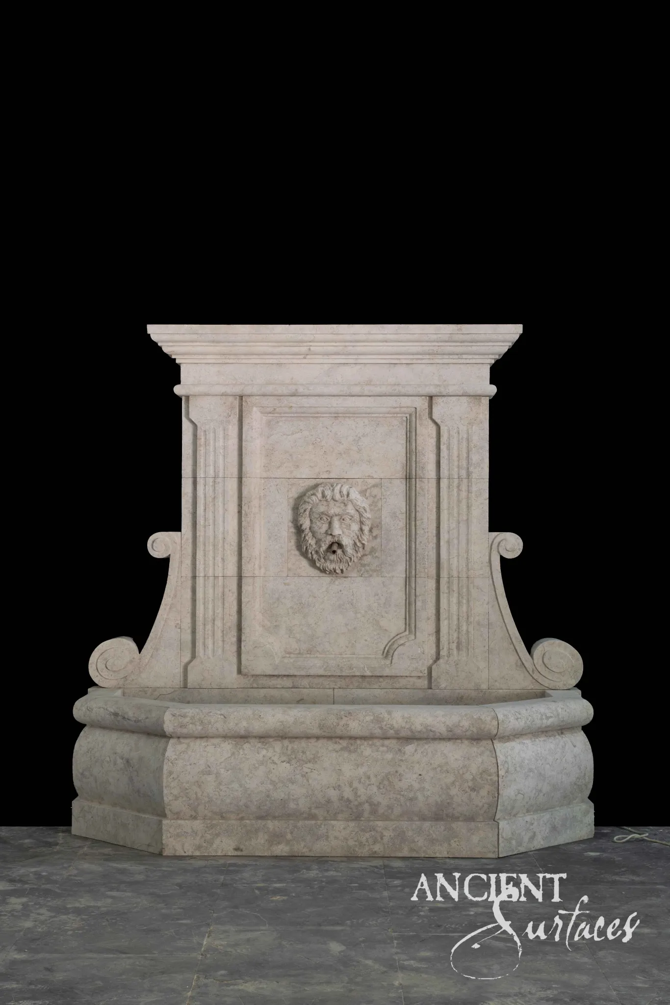 Reclaimed antique limestone fountain surround from Ancient Surfaces with a carved bearded mask medallion, fluted scroll brackets and an octagonal stepped base